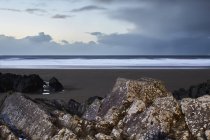 Vista del paisaje marino detrás de las rocas por debajo del cielo nublado, Devon, Reino Unido - foto de stock