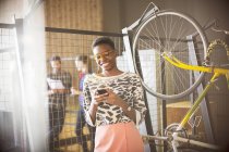 Smiling businesswoman texting on cell phone next to bicycle — Stock Photo