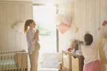 Schwangere Mutter und Tochter schmücken sonniges Kinderzimmer — Stockfoto