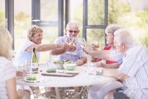 Senior adults toasting wine glasses at patio lunch — Stock Photo