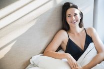 Усміхнена жінка розслабляється в ранковому ліжку — стокове фото