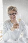 Улыбающийся мужчина пьет белое вино — стоковое фото
