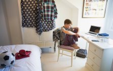 Скучный мальчик делает домашнее задание в спальне — стоковое фото