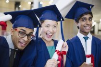 Retrato entusiasta graduados universitários em boné e vestido segurando diplomas — Fotografia de Stock