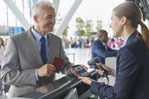 Représentant du service à la clientèle scannant la carte d'embarquement QR code du téléphone intelligent au comptoir d'enregistrement de l'aéroport — Photo de stock
