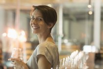 Retrato mujer sonriente degustación de vino en bodega sala de degustación - foto de stock