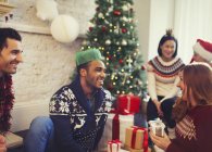 Freunde öffnen Weihnachtsgeschenke im Wohnzimmer — Stockfoto