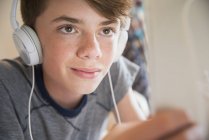 Крупним планом хлопчик з навушниками, що слухають музику на цифровому планшеті — стокове фото