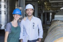 Portrait confident winery employees in hard hats in cellar — Stock Photo