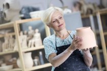 Ältere Frau hält Töpfervase im Atelier — Stockfoto