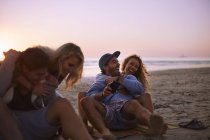 Playful couples hanging out on sunset beach — Stock Photo