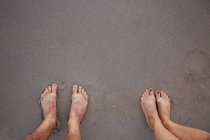 Point de vue personnel couple pieds nus debout dans le sable mouillé sur la plage — Photo de stock