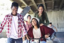 Teenage friends with skateboards and BMX bicycle at skate park — Stock Photo
