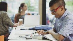 Чоловік студент коледжу робить математичне домашнє завдання з підручником і калькулятором — стокове фото