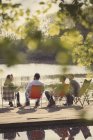 Friends talking at sunny lakeside dock — Stock Photo