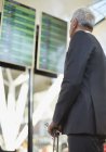 Homme d'affaires regardant vers le haut au tableau de départ d'arrivée à l'aéroport — Photo de stock