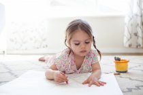 Girl on floor drawing with crayons — Stock Photo