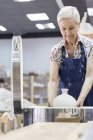 Mujer mayor colocando cerámica en el horno en el estudio - foto de stock