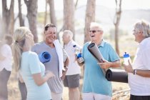 Інструктор з йоги розмовляє з старшими чоловіками після уроків у парку — стокове фото