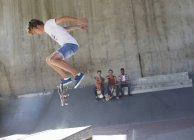 Teenage boy flipping skateboard at skate park — Stock Photo