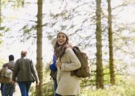 Enthusiastic woman with backpack hiking in sunny woods — Stock Photo