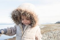 Girl in fur hood jacket walking on beach — Stock Photo