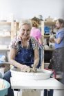 Portrait smiling senior woman using pottery wheel in studio — Stock Photo