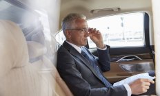 Бизнесмен с документами едет на заднем сиденье городской машины — стоковое фото