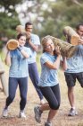 Determined people running with logs on boot camp obstacle course — Stock Photo