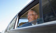 Homme d'affaires souriant regardant par la fenêtre de la voiture de ville — Photo de stock