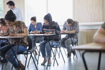 Estudantes universitários fazendo teste em mesas de aula — Fotografia de Stock