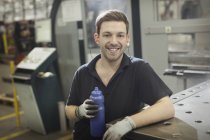 Portrait smiling worker with water bottle in steel factory — Stock Photo