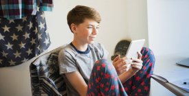 Мальчик в пижаме с цифровым планшетом в спальне — стоковое фото
