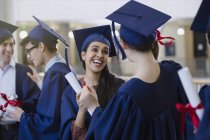 Feliz estudiante universitaria graduada con gorra y vestido y diplomas celebrando - foto de stock