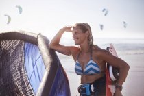 Mulher sorridente com equipamento kiteboard na praia — Fotografia de Stock