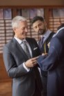 Tailor and businessman examining suit in menswear shop — Stock Photo