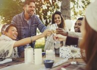 Amigos brindar copas de champán en la mesa del patio de la fiesta de cumpleaños - foto de stock