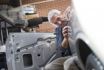 Focused auto body worker examining panel on car — Stock Photo