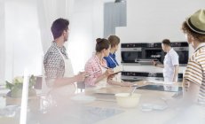 Estudantes tomando notas e assistindo professor de chef no forno na cozinha da aula de culinária — Fotografia de Stock