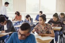 Professor beobachtet College-Studenten bei der Prüfung am Schreibtisch im Klassenzimmer — Stockfoto