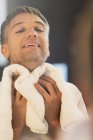 Mann wischt sich Hals am Badezimmerspiegel ab — Stockfoto