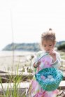 Девушка собирает пасхальные яйца в корзине на пляже — стоковое фото