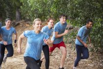 Equipe sorrindo correndo no campo de inicialização curso de obstáculo — Fotografia de Stock