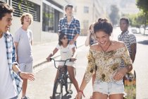 Adolescente riéndose con amigos en la soleada calle urbana - foto de stock
