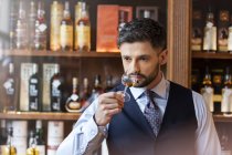 Хорошо одетый мужчина пробует виски — стоковое фото