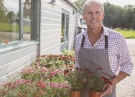 Portrait smiling plant nursery owner with potted flowers — Stock Photo