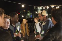 Young friends talking and drinking at rooftop party — Stock Photo