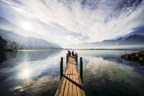 Casal na beira da doca sobre lago tranquilo ensolarado, Suíça — Fotografia de Stock