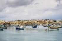 Barcos amarração fora da cidade à beira-mar, Marsaxlokk, Malta — Fotografia de Stock