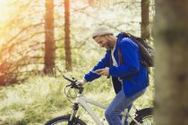 Людина гірських велосипедах текстові повідомлення з мобільного телефону в лісі — стокове фото
